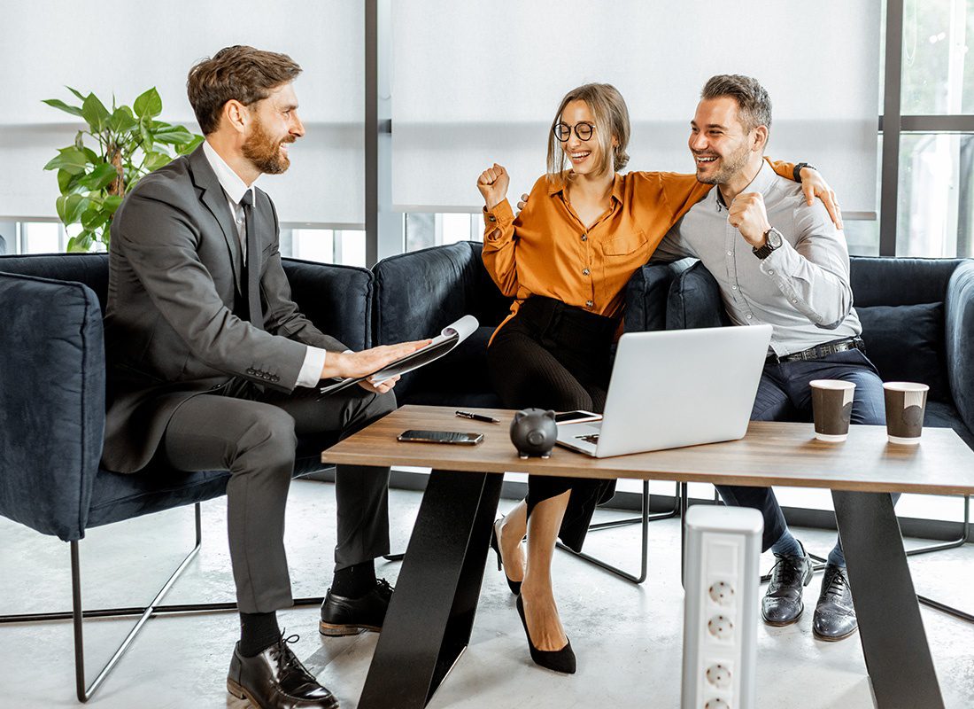 About Our Agency - Happy Couple Sitting With Their Agent in an Office Getting Good News