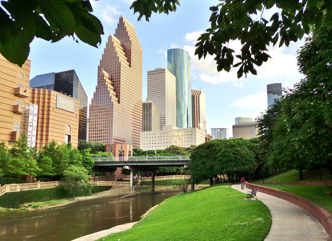 Contact - Bicyclist on Paved Bike Path in Buffalo Bayou Park, With the Skyline of Downtown Houston in the Background